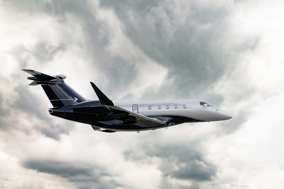 An Embraer Praetor 500 flies in a cloudy sky.